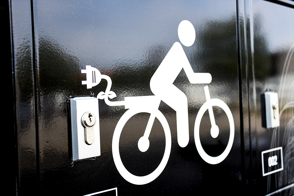 närbild elcykelladdningsskåp en vit illustration med en männsiak som cyklar och ett eluttag