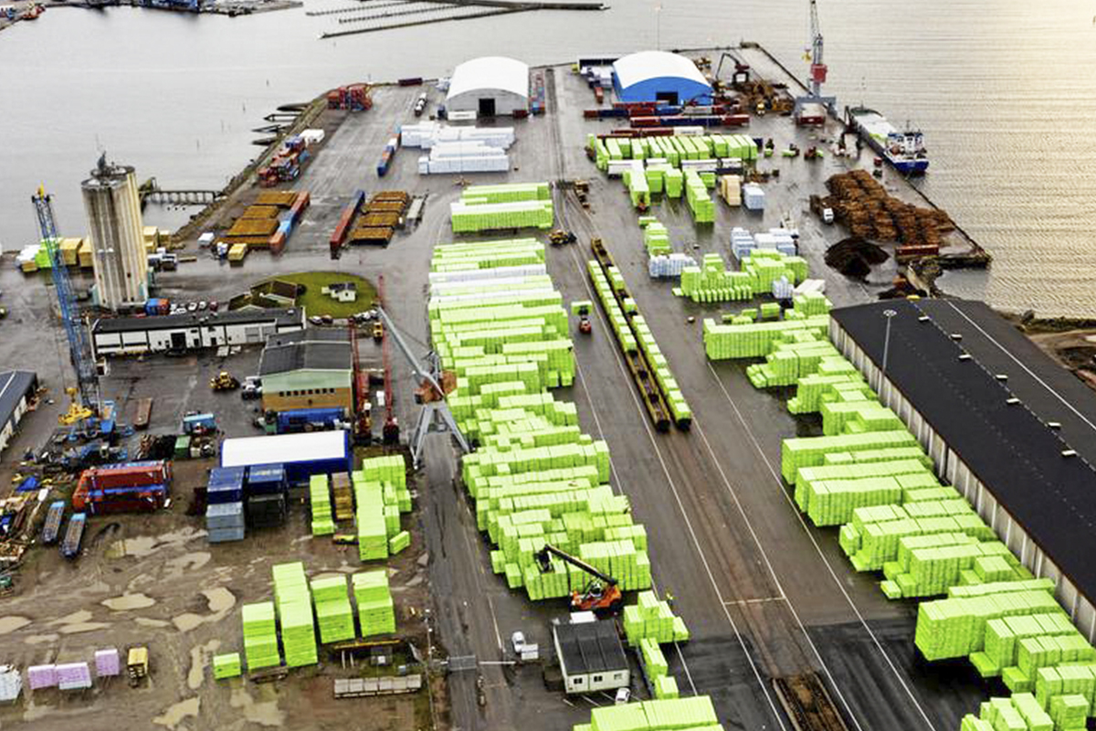 flygbild över frakthamn med många containrar, båtar och förråd